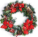 Photo of a beautiful circular wreath decorated with pine cones, pine tree fronds, and red poinsettas. The entire wreath is coated with a slight dusting of snow.
